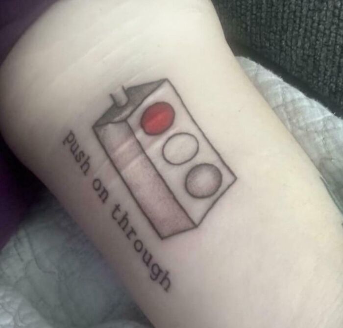 Tattoo fail showing a block with three circles and text push on through on a person's arm.
