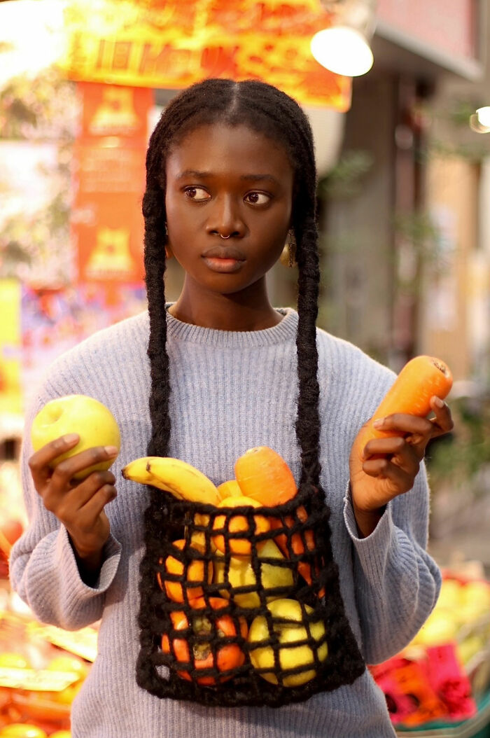 Artist creates hair sculpture resembling net bag filled with fruits.