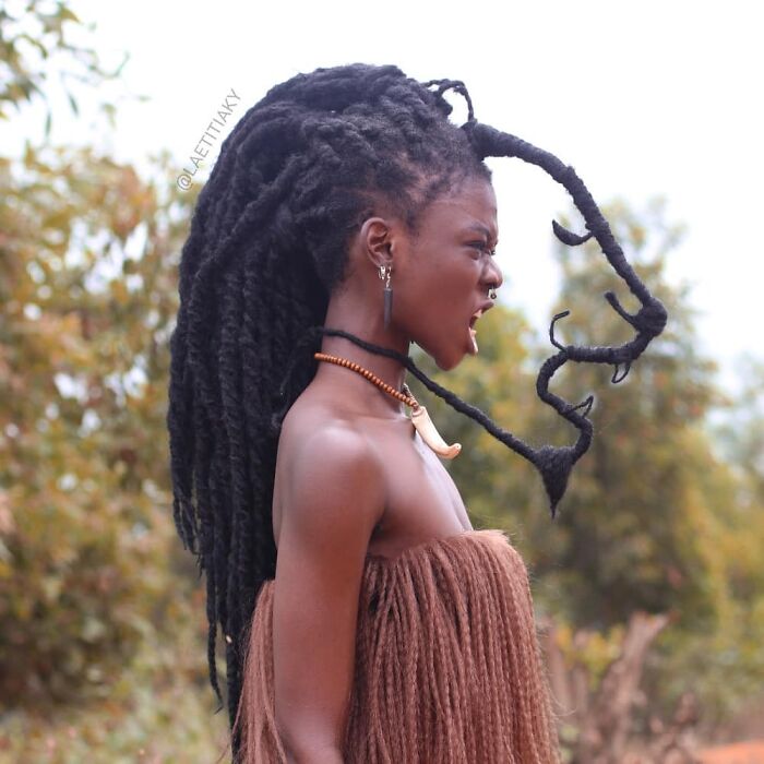 Artist with hair sculpted into intricate design, showcasing creative expression.