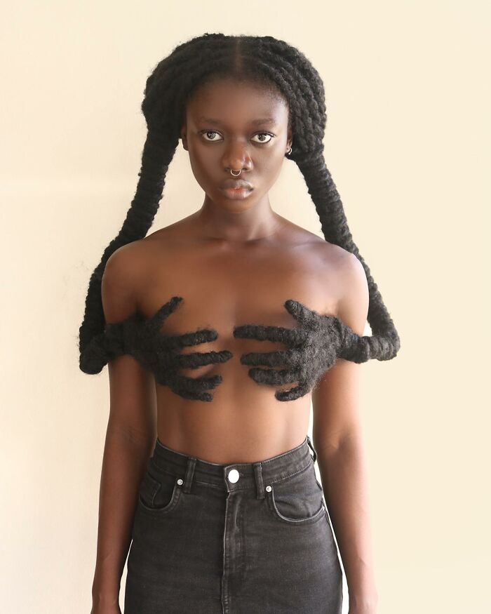 Woman with hair sculpted into hands covering chest, showcasing unique hair sculpture artistry.