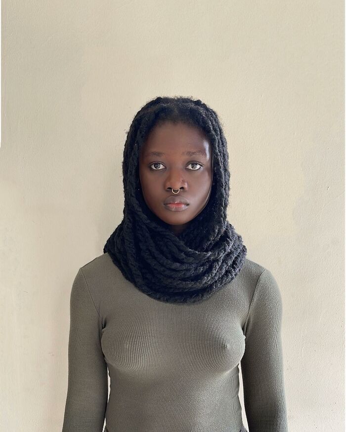 Artist uses her hair creatively, sculpting it into an elegant, scarf-like design, wearing a green top.