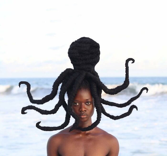 Artist's hair sculpture resembling an octopus, showcasing creativity against a beach backdrop.