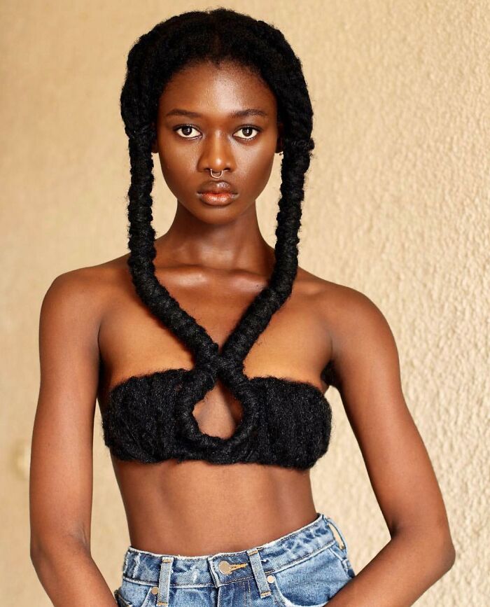 Artist creates hair sculpture, featuring braided design styled into a top, paired with denim jeans.