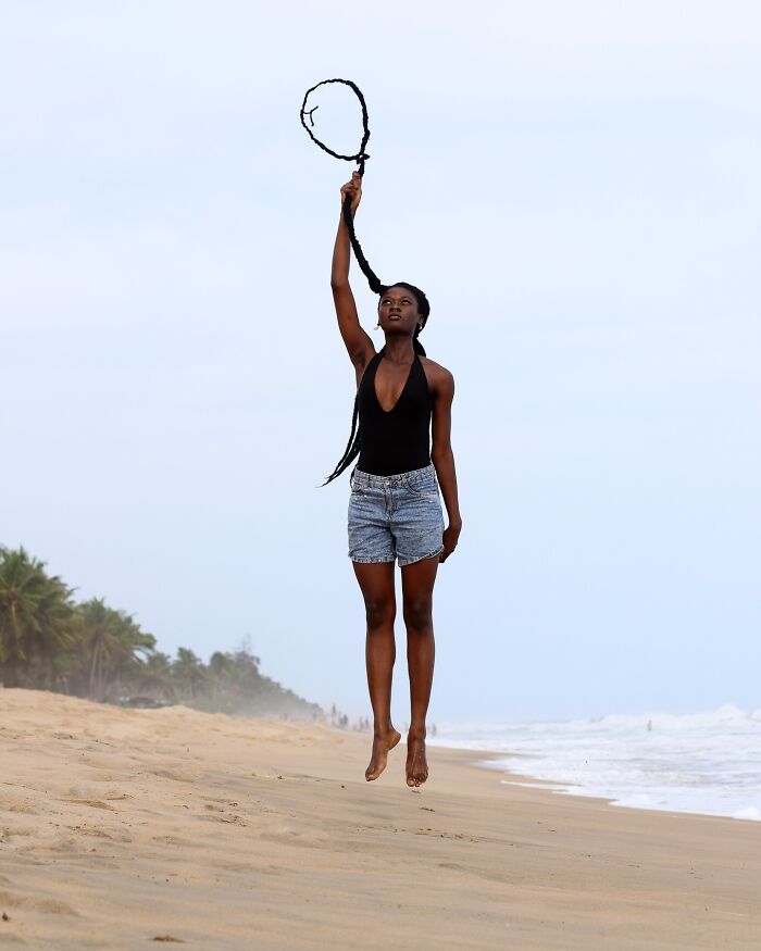 Artist on a beach with her hair shaped into an incredible sculpture, resembling a loop above her head.