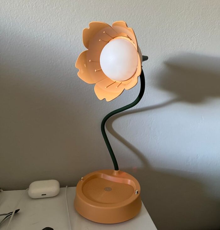 Flower-shaped lamp with a curved green stem on a table, one of the items to unleash your inner child.