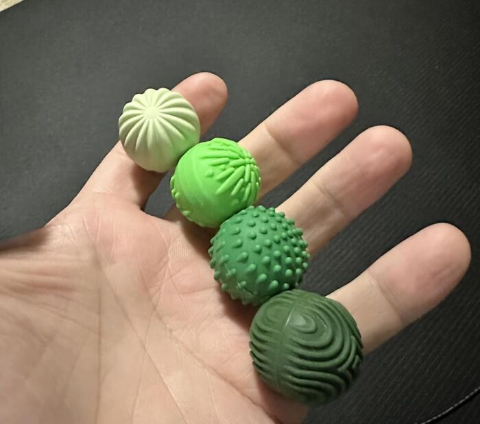 Hand holding four textured green sensory balls, one of 23 items to unleash your inner child and spark fun.