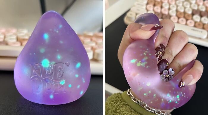 Purple Nee Doh stress ball with glowing blue dots, shown resting on a desk and being squeezed by a hand with decorated nails.