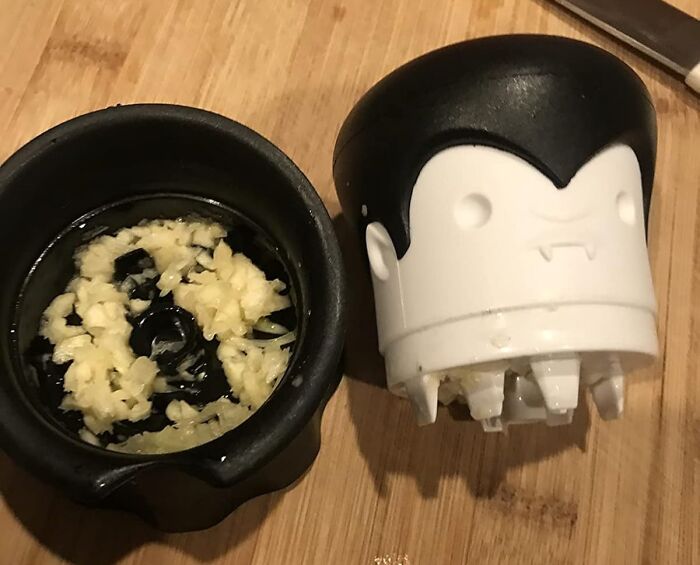 Garlic press shaped like a cartoon vampire on a wooden cutting board, a playful item to unleash your inner child.
