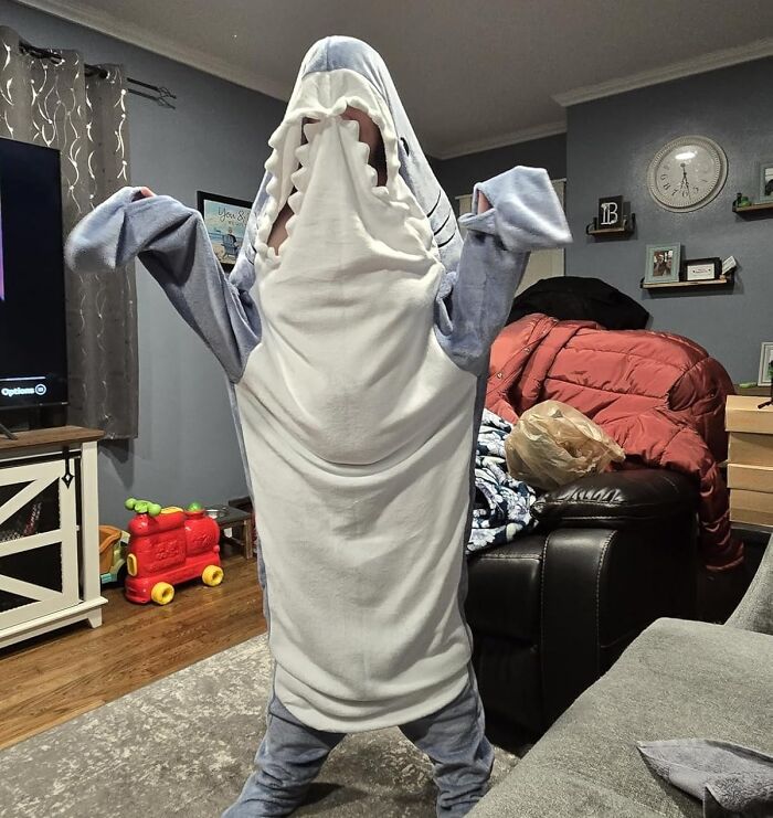 Person wearing a playful shark costume indoors, showcasing fun items to unleash your inner child at any age.