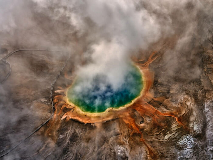 Aerial view of vibrant hot spring surrounded by mist, showcasing jaw-dropping nature photography.