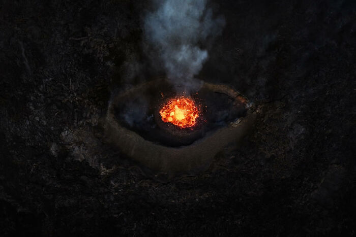 Aerial view of an active volcano with glowing lava and smoke, showcasing award-winning nature photography.