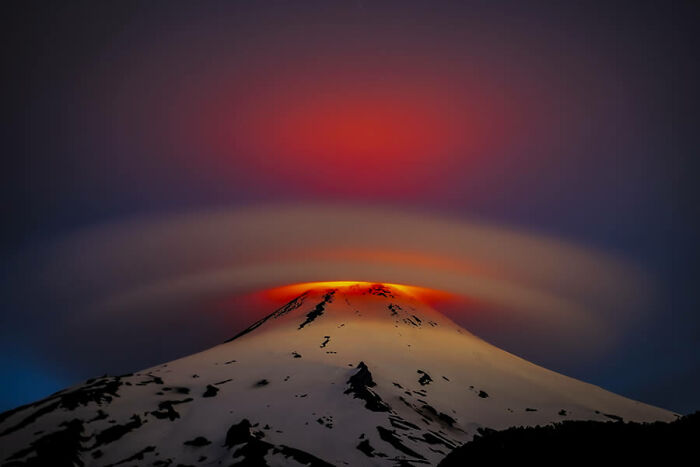 Stunning nature photo of a snow-capped volcano with a glowing red and orange sky at dusk.