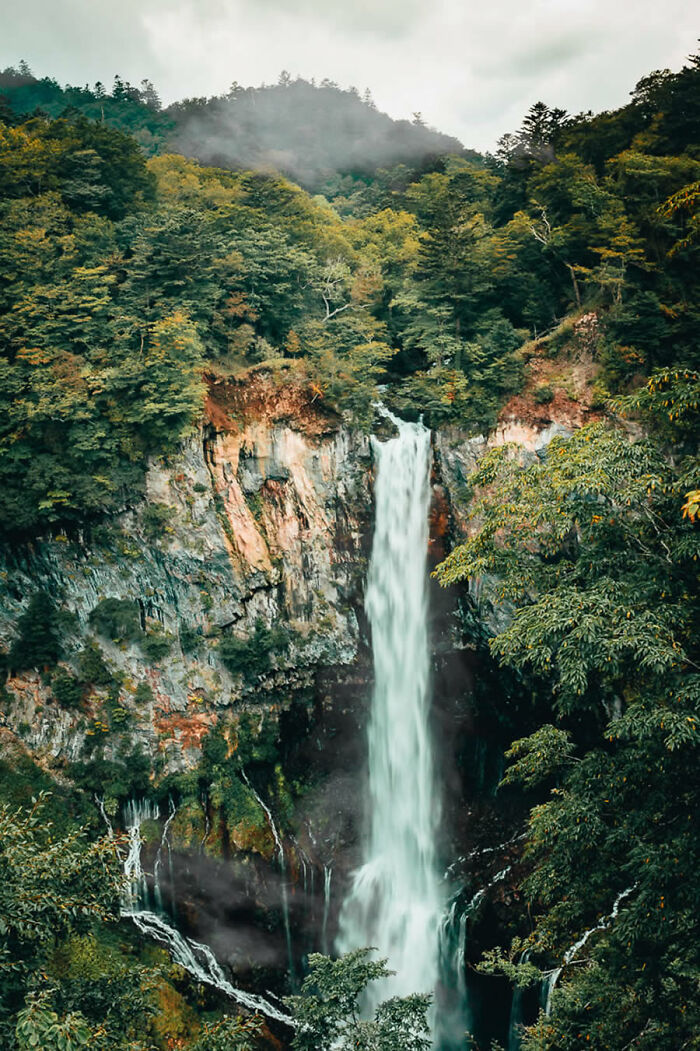 Majestic waterfall cascading down a cliff, surrounded by lush forest, showcasing award-winning fine art nature photography.