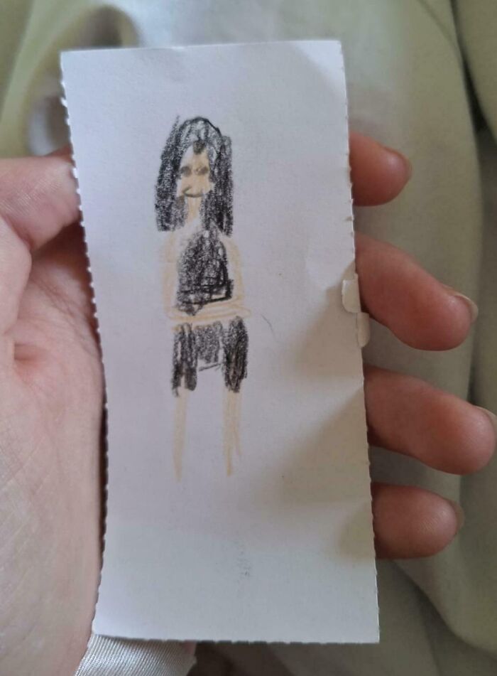 Hand holding a small paper with a childlike drawing of a person, evoking pure and uplifting moments.