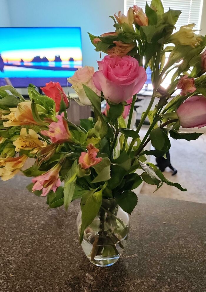 Ramo de flores coloridas en jarrón sobre mesa, símbolo de momentos positivos y conmovedores para la humanidad.