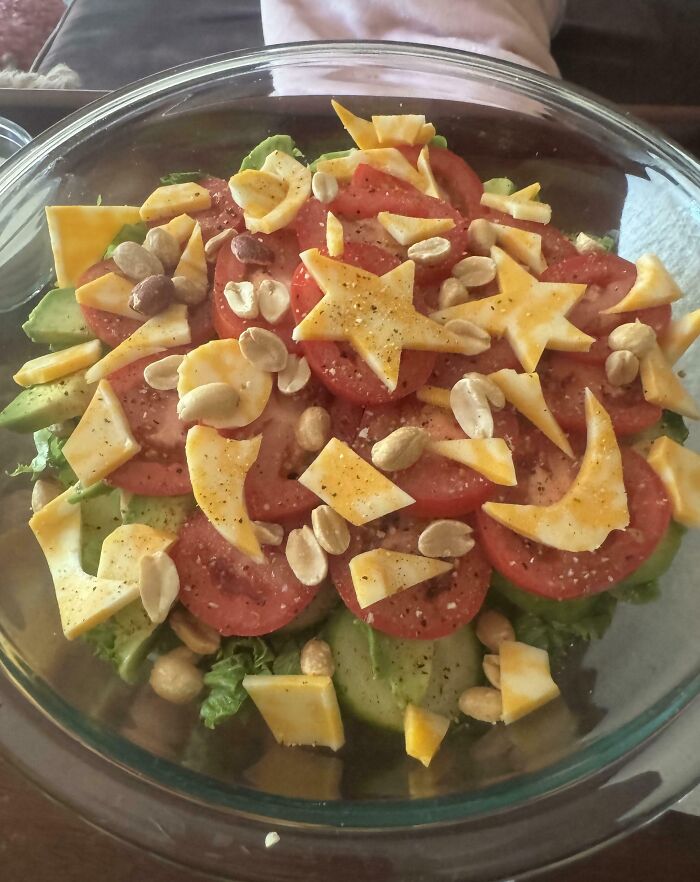 Ensalada colorida con tomate, queso en forma de estrellas y cacahuates, representando momentos positivos y conmovedores.
