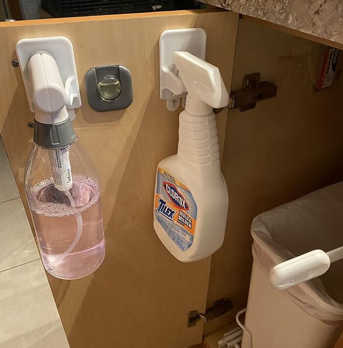 Under-sink organization with spray bottles hung on adhesive hooks for genius home organization finds under $20.
