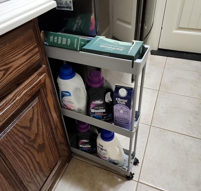 Sliding narrow cabinet organizer with laundry detergents and cleaning supplies, a genius organization find under $20 for home.
