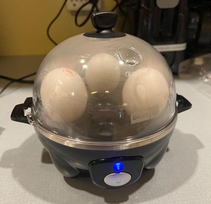 Electric egg cooker with clear lid cooking eggs, an essential time saver for busy kitchen routines.