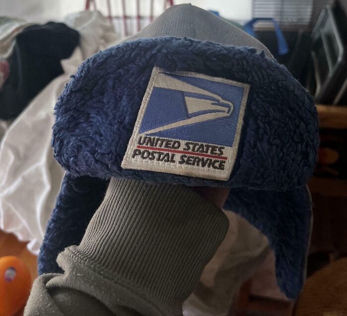 Blue winter hat with United States Postal Service logo held indoors capturing pure and uplifting moments in daily life.
