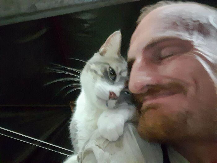 Man happily snuggling with a cat, showcasing the joy of animal adoption.