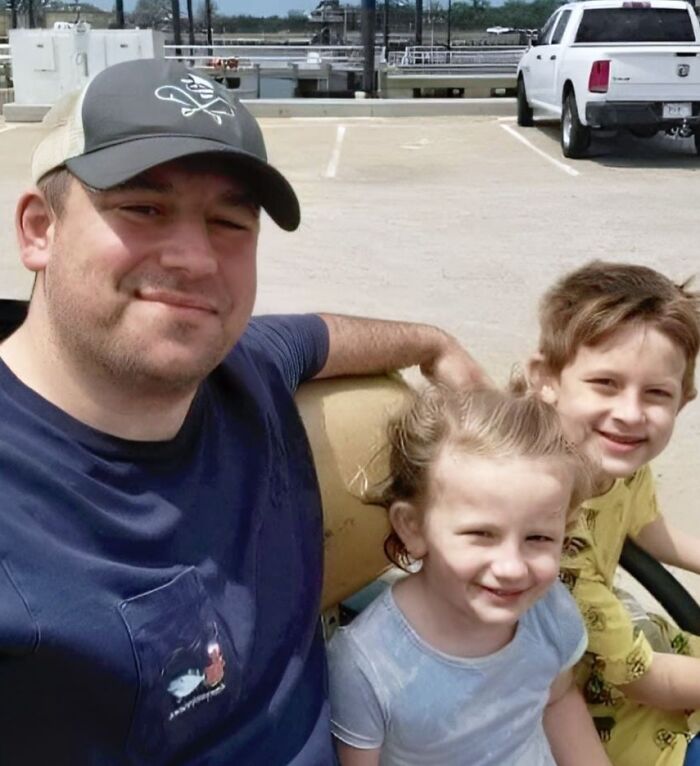 Man in a hat with two smiling children, outdoors near parked vehicles, illustrating a forbidden story moment.
