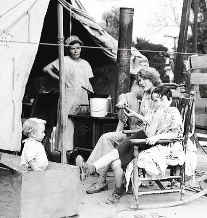 Family gathered outside a tent, sharing a moment during the Great Depression era.