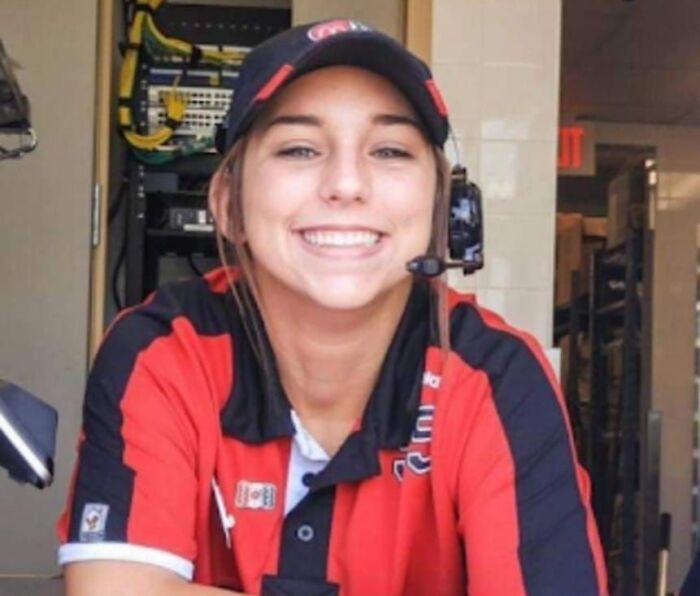 Smiling employee in a red and black uniform with headset, representing interesting stories from around the world.