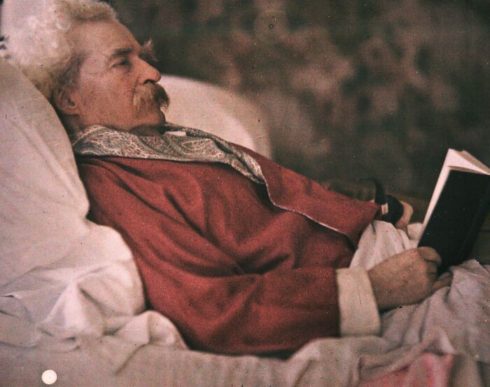 Rare color photo of a famous historical figure reclining and reading a book in a cozy indoor setting