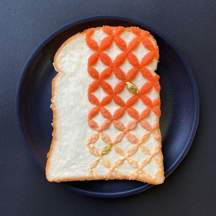 Creative toast design with orange geometric patterns by Japanese artist on a black plate.