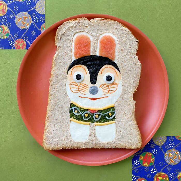 Creative toast design featuring a cute animal character on a slice of bread, displayed on a red plate.