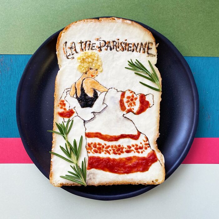 Creative toast design featuring a painted Parisian woman in a dress on a black plate, with rosemary garnish.
