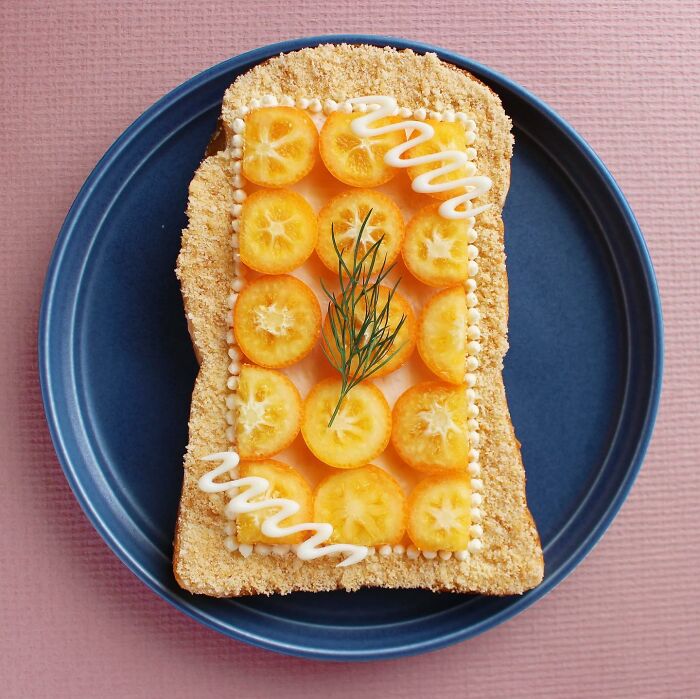 Creative toast design with orange slices and dill on a blue plate.