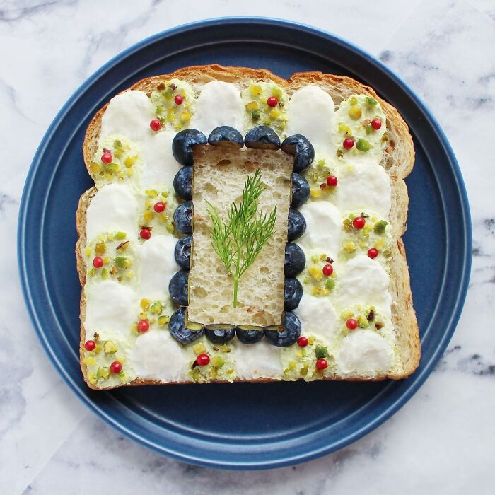Creative toast design with blueberries and dill on a blue plate.