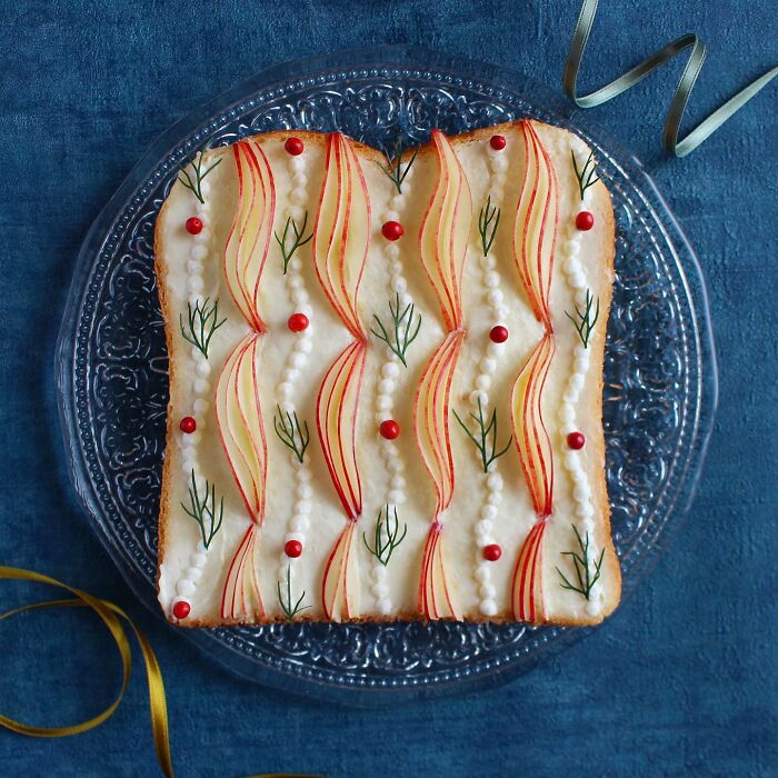 Creative toast design with red fruits, green herbs, and pear slices on a glass plate for a Japanese artist's new collection.