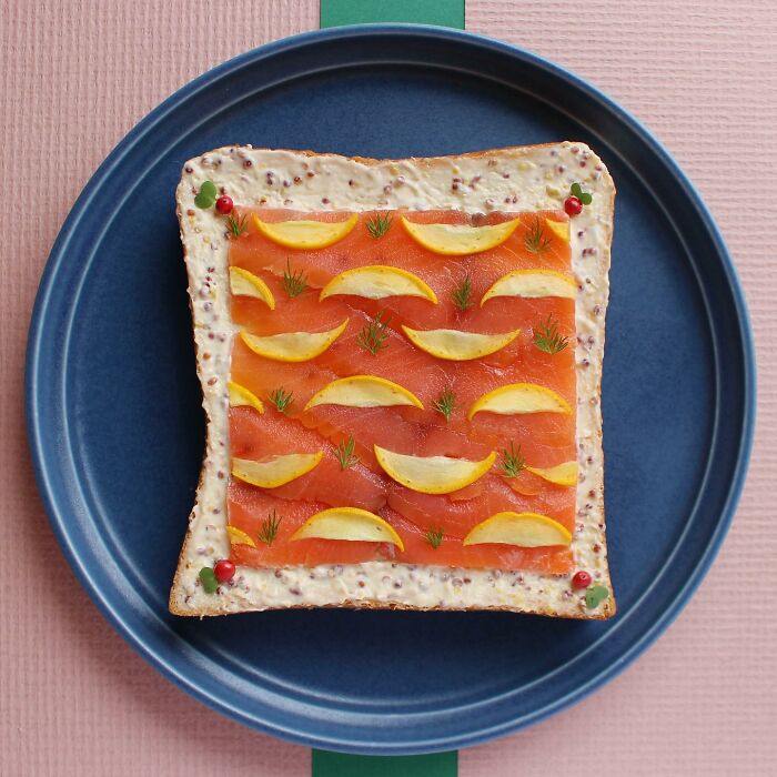 Creative toast design featuring salmon, lemon slices, and dill arranged on a blue plate, showcasing Japanese artistry.