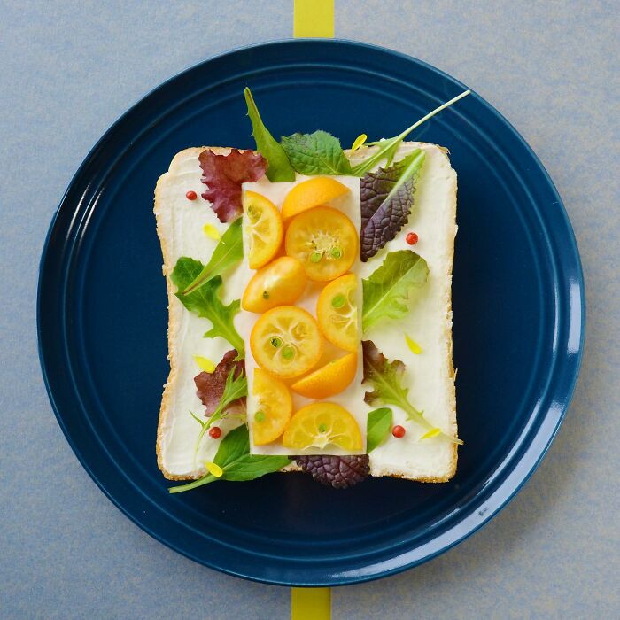 Creative toast design featuring vibrant kumquats and greens on a blue plate.