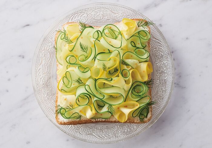 Creative toast design featuring cucumber and dill on a decorative plate.