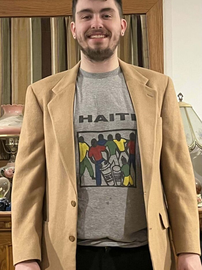 Person wearing a tan blazer and a graphic t-shirt with "Haiti" text, showcasing a hidden gem found at Goodwill.