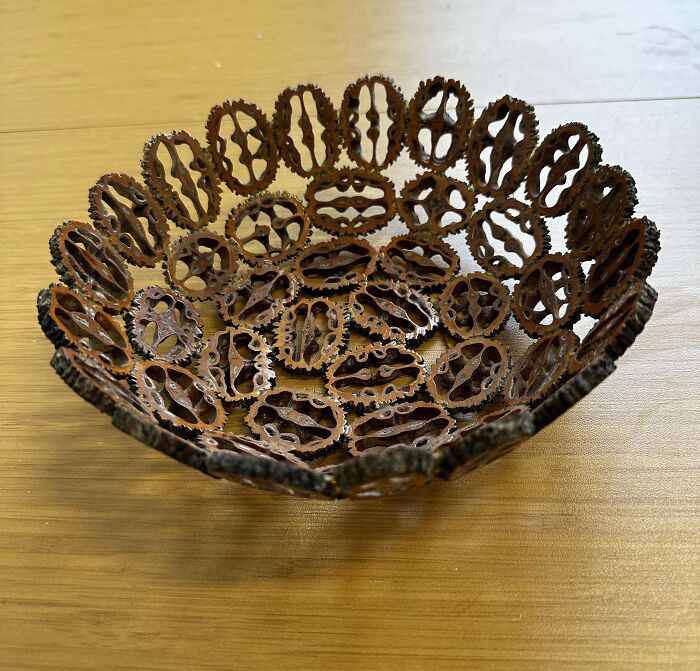 A decorative bowl made from metal chains, a hidden gem found at Goodwill, placed on a wooden table.