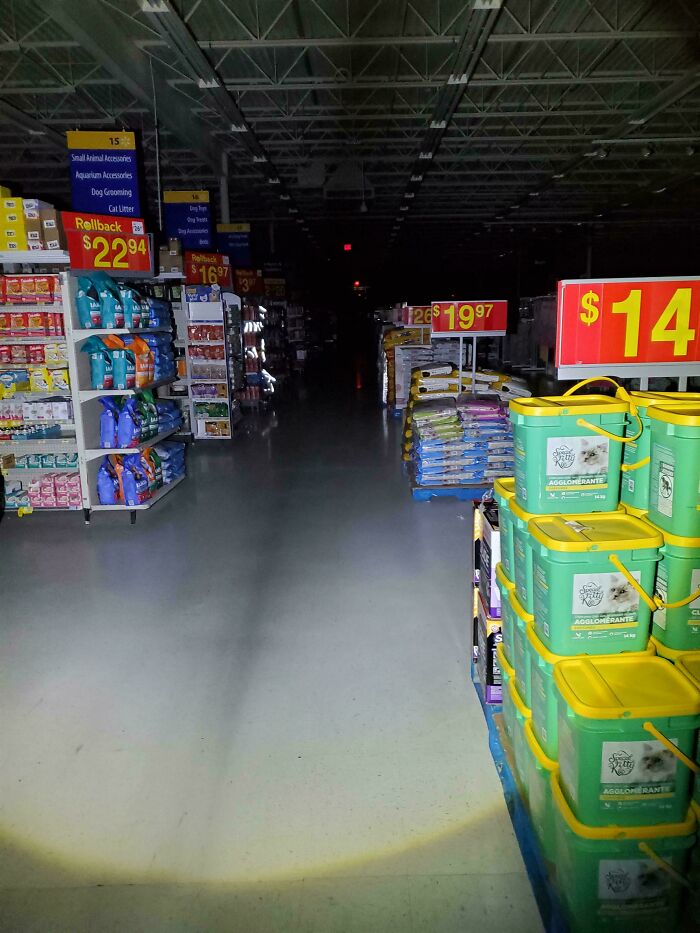Dimly lit store aisle with pet supplies illuminated under flashlight, capturing a creepy atmosphere people had to share.