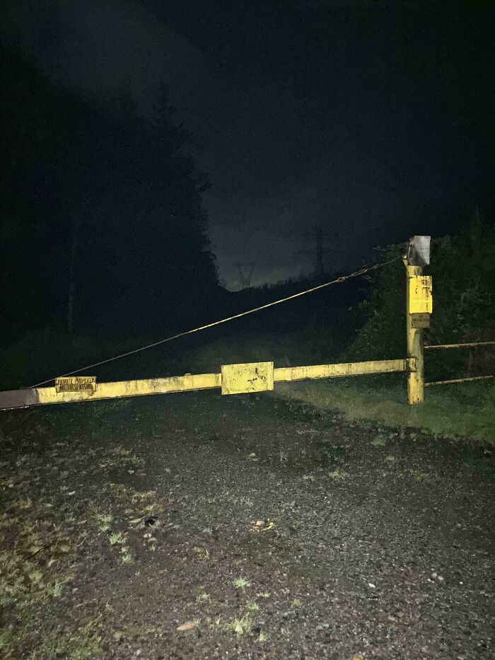 Yellow gated barrier across dark gravel path in the woods at night, creating a creepy atmosphere people had to share.