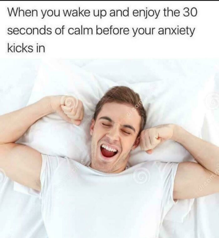 Man stretching and yawning in bed, humorously depicting a brief moment of calm before anxiety begins.