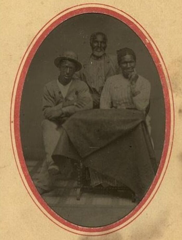 Three African American men sitting around a table, showcasing strength in a powerful historical photo over a century ago.