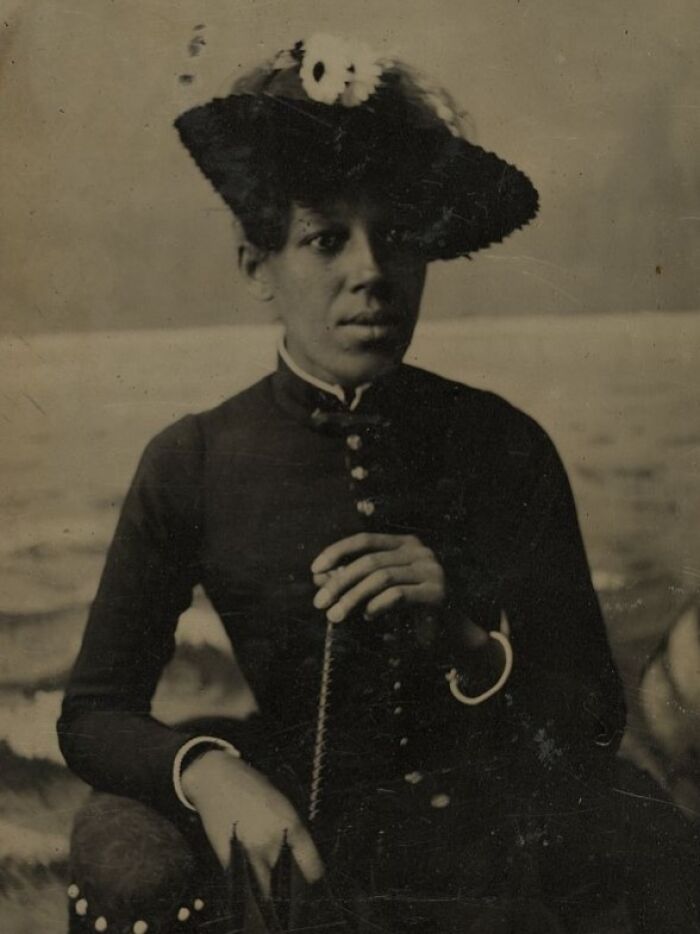 African American woman dressed in early 1900s attire, showcasing strength and resilience from a century ago.