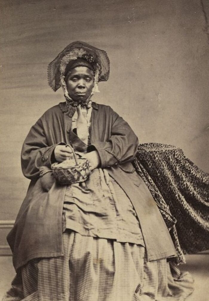 African American woman from over a century ago wearing period clothing and holding a small basket, showing strength and resilience.