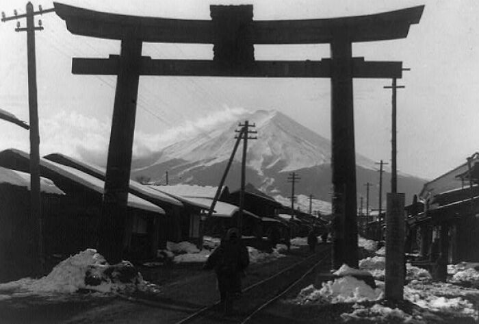 Torii gate and Mount Fuji in a snowy 1800s Japan village, showing traditional streets and early infrastructure.