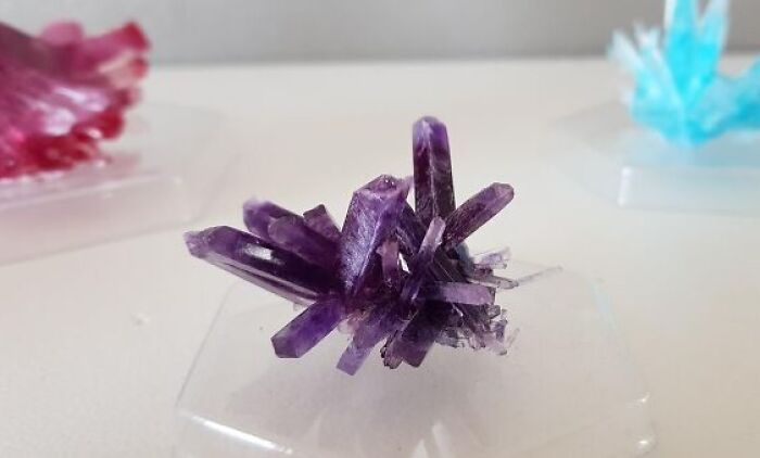 Purple crystal cluster displayed on a clear stand among unique Amazon finds that hover between genius and why does this exist.