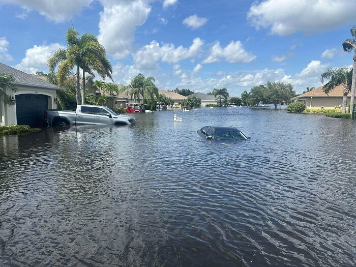 Flooded residential street in the US with submerged cars and houses capturing current life through American eyes.