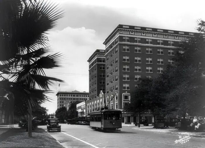 Vintage streetcar and early 20th century cars on an American city street showcasing life in America 100 years ago.